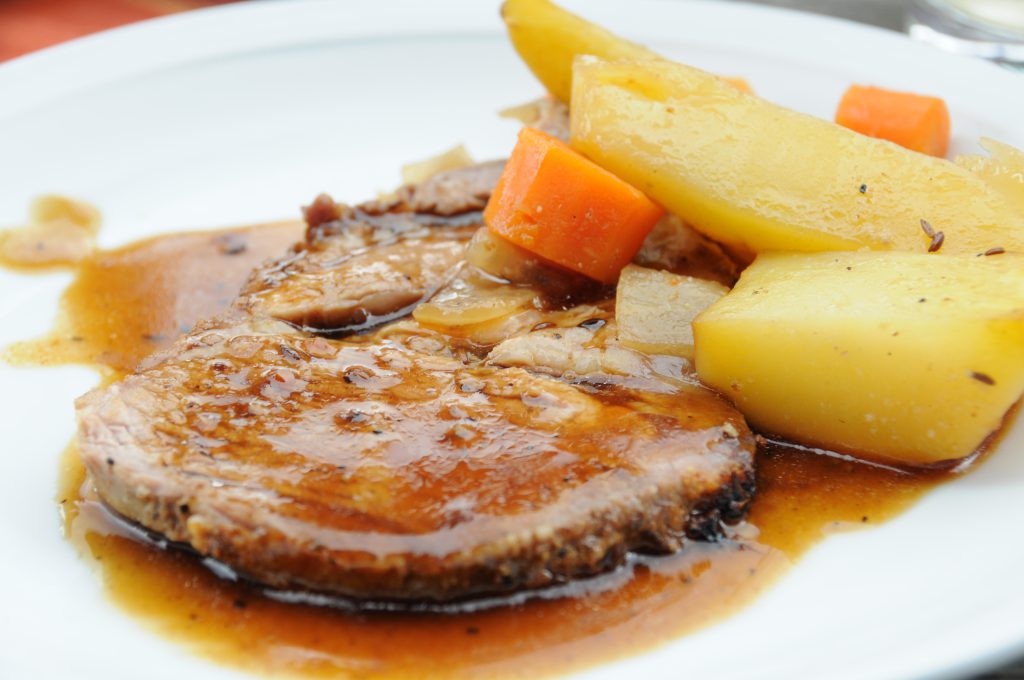 Braten mit Kartoffeln und Karotten auf weißem Teller