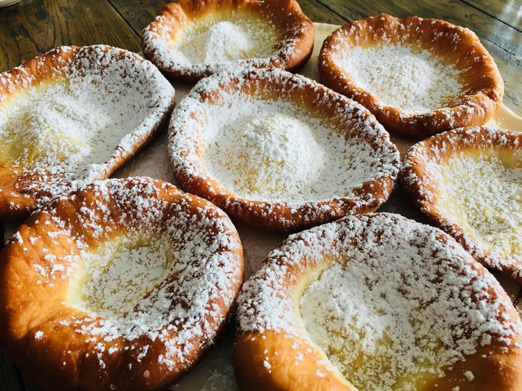 Mehrere Bauernkrapfen mit Staubzucker auf Holztisch