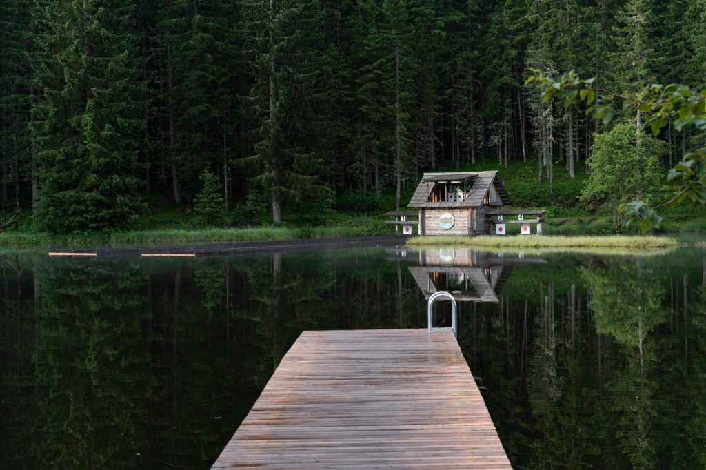 Holzsteg am See mit Blick auf Hütte im Wald